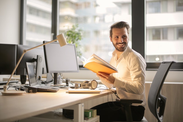 Insurance Agency California | Man Sitting at His Office Desk Holding a Book